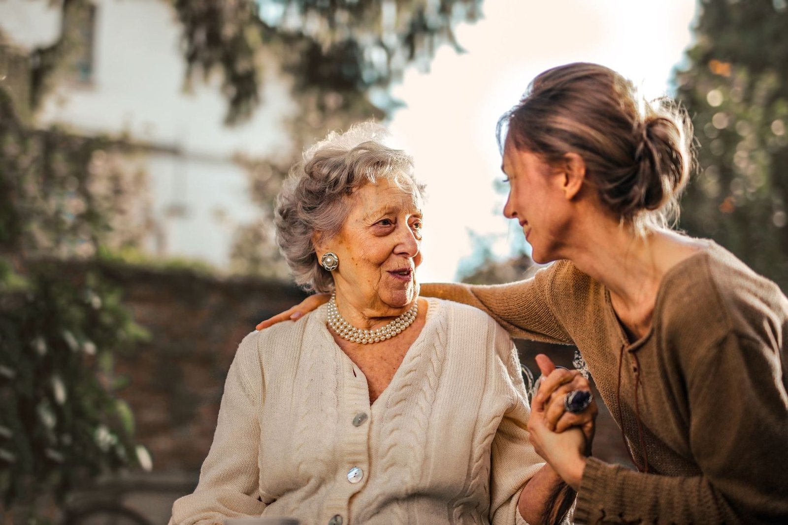 An adult daughter and her mother laughing together in the garden